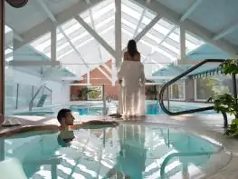 Huéspedes en la piscina interior con cubierta de cristal del Hotel Spa A Quinta da Auga en Santiago
