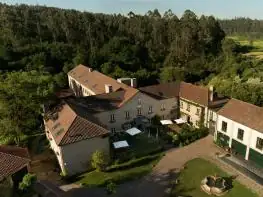 Vista aérea del conjunto de edificios de piedra y jardines de A Quinta da Auga entre bosques