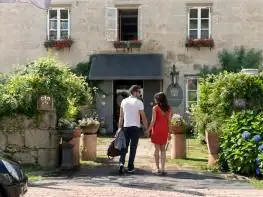 Pareja llegando a la entrada de piedra con flores del Hotel Relais & Châteaux A Quinta da Auga