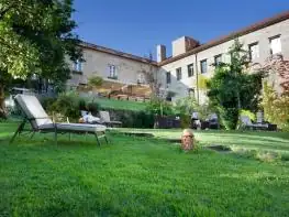 Jardín con césped y tumbonas frente a la fachada del hotel A Quinta da Auga en un día soleado