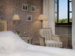 Rincón de lectura con butaca y lámparas junto a la cama en una habitación de A Quinta da Auga