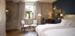 Habitación con dos camas, butacas junto a la ventana y suelo de madera en A Quinta da Auga