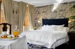 Suite con cama de cabecero capitoné y desayuno servido en la habitación de A Quinta da Auga