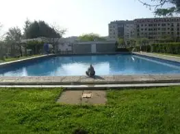 Piscina exterior rectangular rodeada de césped en los jardines del Balneario Acuña