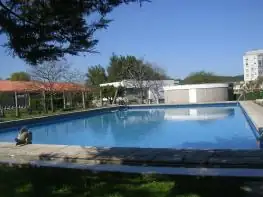 Piscina al aire libre con árboles y cielo despejado en el recinto del Balneario Acuña