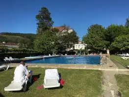 Huéspedes tomando el sol en tumbonas sobre el césped junto a la piscina del Balneario Acuña