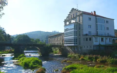 Edificio del Balneario Acuña junto al río y el puente de piedra de Caldas de Reis