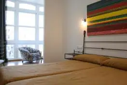 Habitación doble con dos camas y cuadro de rayas de colores en el Balneario Acuña