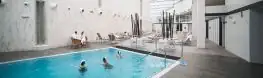 Bañistas en una piscina interior con paredes blancas del Arnoia Caldaria Hotel Balneario