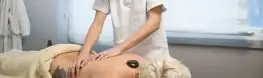 Masaje con piedras calientes sobre la espalda en una cabina del Balneario Arnoia