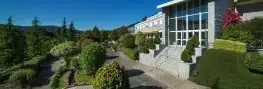 Jardines con escalinata y entrada acristalada del Arnoia Caldaria Hotel Balneario
