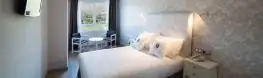 Habitación doble luminosa con cabecero blanco y cojines en el Balneario Arnoia