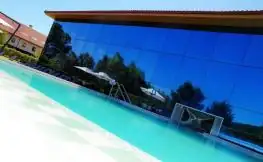 Piscina exterior junto a la fachada acristalada que refleja el cielo en Iberik Augas Santas