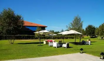 Jardín con sombrillas y sofás de exterior junto a los edificios del balneario Augas Santas