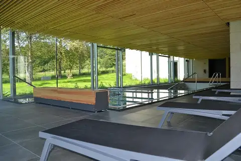 Zona de reposo con tumbonas junto a la piscina termal acristalada del Balneario Caldas de Partovia