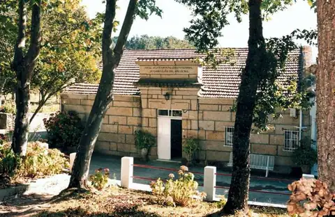 Edificio histórico de piedra entre árboles en el recinto del Balneario Caldas de Partovia