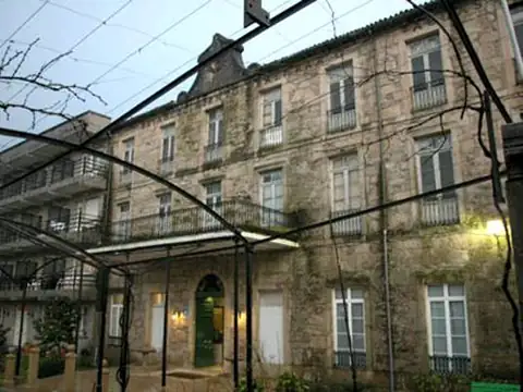 Fachada histórica de piedra con balcones bajo la pérgola del Hotel Balneario de Caldelas de Tui