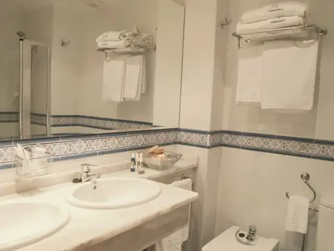 Baño de habitación con doble lavabo de mármol y toallas en el Hotel Balneario de Compostela