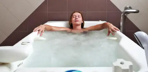Mujer relajada en una bañera de hidromasaje burbujeante en el Hotel Balneario de Carballo
