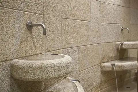 Pilas de granito con grifos para tomar el agua en la sala de fuentes del Balneario de Carballo
