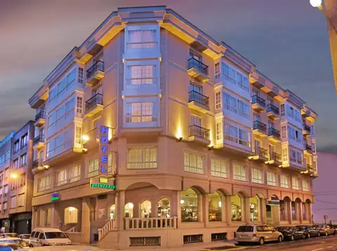 Fachada iluminada al anochecer del edificio de galerías del Hotel Balneario de Carballo