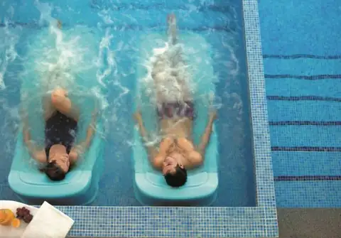 Dos personas flotando sobre camas de agua en la piscina del Gran Balneario de Guitiriz