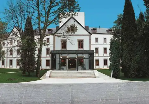 Fachada principal con entrada acristalada y jardines del Iberik Gran Balneario de Guitiriz