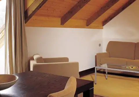 Salón abuhardillado con vigas de madera y sofás en una suite del Gran Balneario de Guitiriz