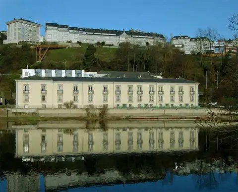Edificio del Hotel Balneario de Lugo reflejado en el río, con la ciudad al fondo