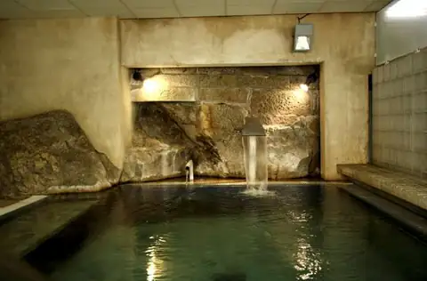 Piscina de agua termal con chorro y pared de roca natural en el Balneario de Baños de Molgas
