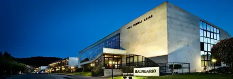Fachada del balneario iluminada al anochecer en el Laias Caldaria Hotel Balneario