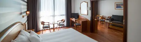 Suite con dormitorio y salón contiguo con sofá en el Laias Caldaria Hotel Balneario