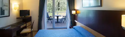 Habitación doble con cama de colcha azul y salida a terraza en Lobios Caldaria Hotel Balneario