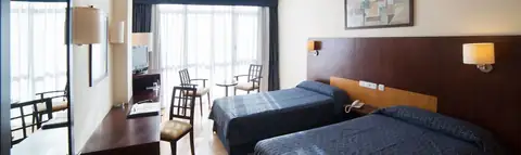 Habitación con dos camas, escritorio y ventanal luminoso en Lobios Caldaria Hotel Balneario