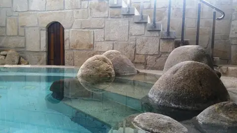 Piscina exterior con grandes cantos rodados y muro de granito en el Balneario de Mondariz