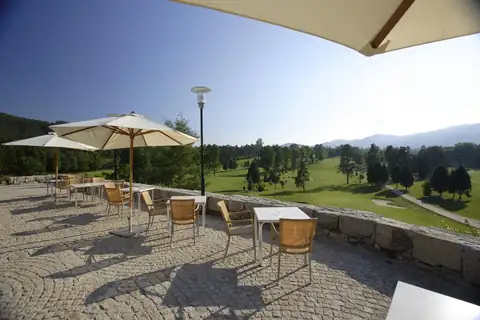 Terraza con sombrillas y mesas frente al campo de golf del Balneario de Mondariz