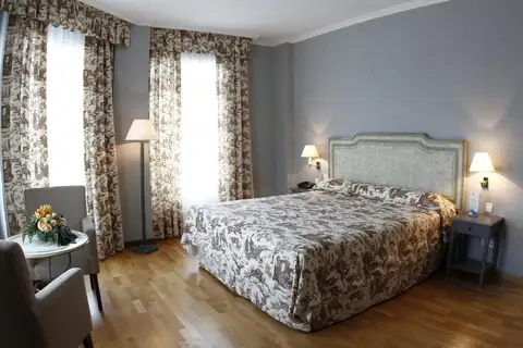 Habitación doble clásica con colcha estampada y suelo de madera en el Balneario de Mondariz