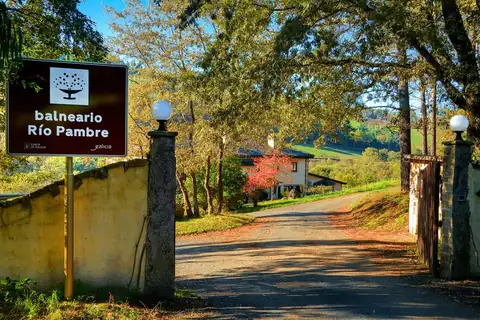 Cartel de entrada y camino entre árboles otoñales al Hotel Balneario Río Pambre en Palas de Rei