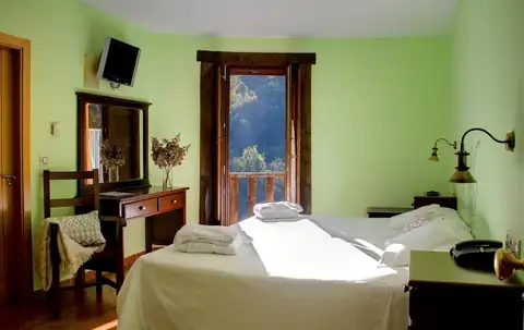 Habitación con paredes verdes, cama, escritorio y balcón en el Hotel Balneario Río Pambre