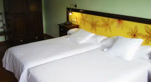 Habitación con dos camas y cabecero decorado con flores amarillas en el Balneario Río Pambre
