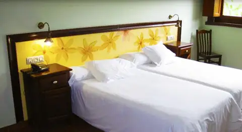 Habitación doble con camas individuales y apliques de lectura en el Hotel Balneario Río Pambre