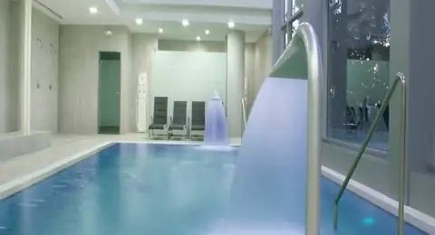 Piscina interior con chorros cervicales y tumbonas al fondo en el Hotel Balneario Baños da Brea