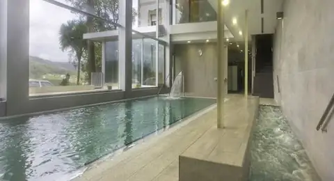 Piscina alargada y canal de agua con paredes acristaladas en el Hotel Balneario Baños da Brea