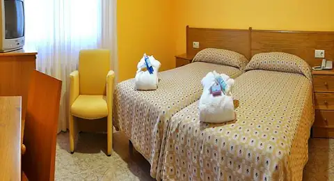 Habitación con dos camas, butaca y escritorio en el Hotel Balneario Baños da Brea