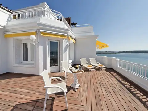 Amplia terraza de madera con tumbonas y vistas a la ría en una suite del Gran Hotel La Toja