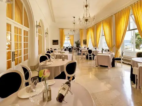 Comedor luminoso con cortinas amarillas, lámpara de araña y mesas vestidas del Gran Hotel La Toja