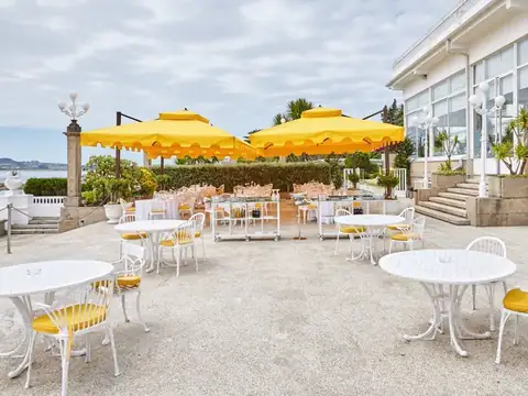 Terraza exterior con sombrillas amarillas y mesas blancas junto a la ría en el Gran Hotel La Toja