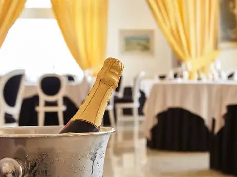 Botella de cava en cubitera con el comedor de mesas vestidas al fondo en el Gran Hotel La Toja
