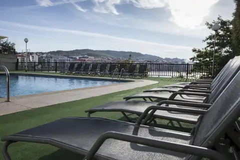 Piscina exterior con tumbonas sobre césped y vistas a la ría en el Gran Talaso Hotel Sanxenxo