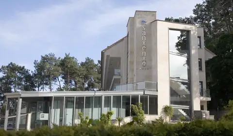 Fachada moderna con el nombre Sanxenxo y edificio acristalado del Gran Talaso Hotel Sanxenxo